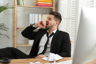 Photo of Lazy employee yawning at table in office