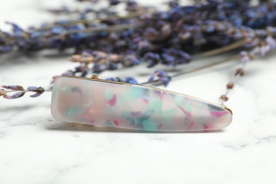 Photo of Beautiful hair clip on white marble table, closeup