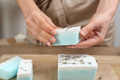 Photo of Woman with natural handmade soap at wooden table, closeup