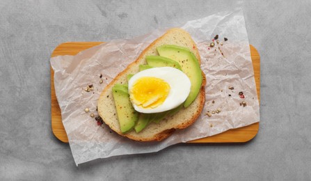 Photo of Delicious sandwich with boiled egg and pieces of avocado on gray table, top view