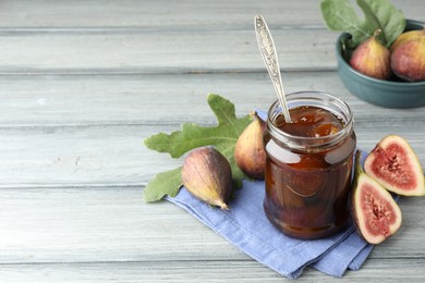 Jar of tasty sweet jam and fresh figs on grey table, space for text