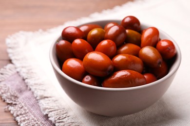 Photo of Fresh Ziziphus jujuba fruits in bowl on table, closeup