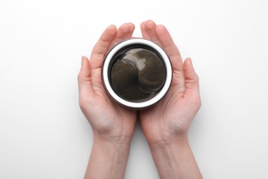 Photo of Woman holding jar with under eye patches on white background, top view. Cosmetic product