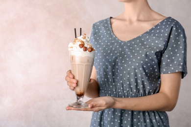 Photo of Woman holding glass with delicious milk shake on light background