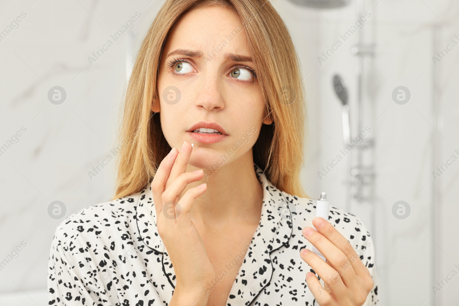 Photo of Woman with herpes applying cream onto lip in bathroom