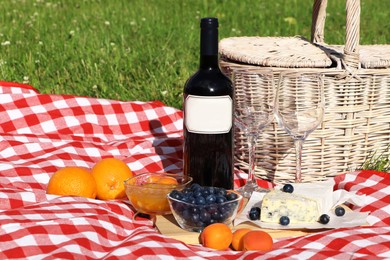 Photo of Picnic blanket with delicious food and wine outdoors on summer day