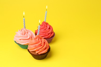 Photo of Delicious birthday cupcakes with bright cream on yellow background. Space for text