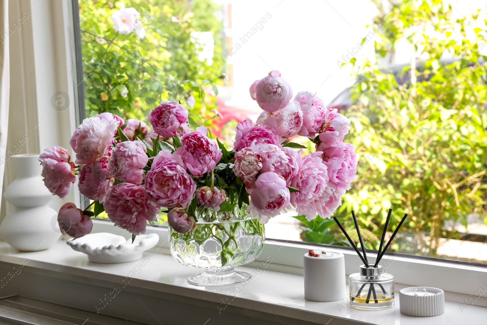 Photo of Beautiful pink peonies in vase on window sill. Interior design