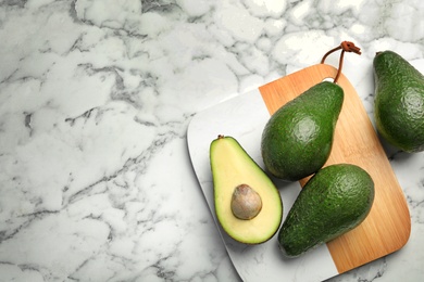 Photo of Delicious ripe avocados on marble table, flat lay. Space for text