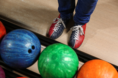 Photo of Person in bowling shoes near rack with balls, above view
