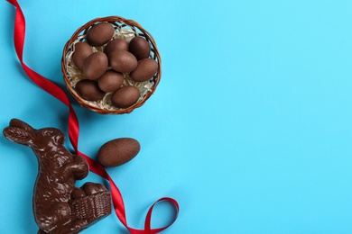 Photo of Flat lay composition with chocolate Easter bunny and eggs on light blue background. Space for text