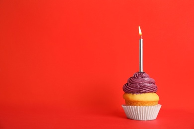 Photo of Birthday cupcake with candle on red background, space for text