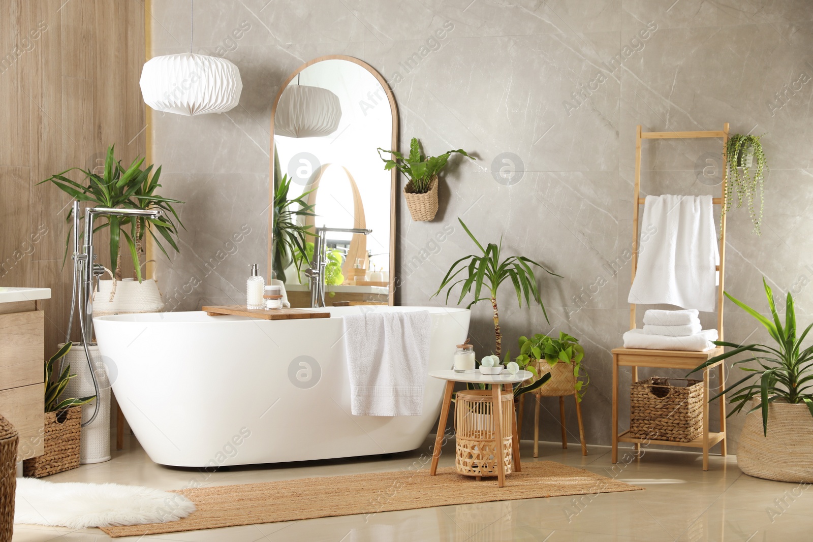 Photo of Modern white tub and beautiful green houseplants in bathroom. Interior design