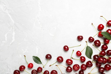 Sweet juicy cherries with leaves on grey marble table, flat lay. Space for text