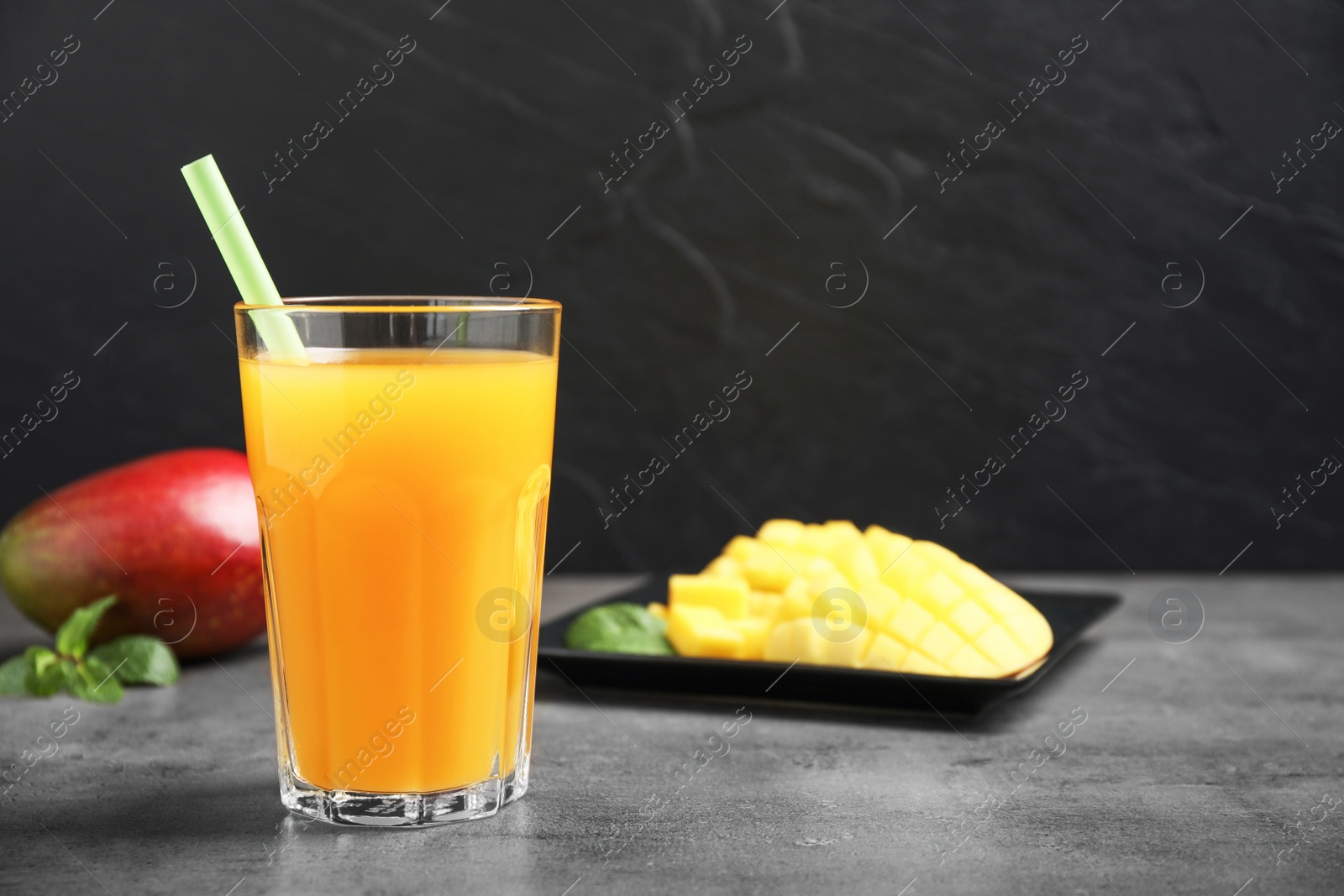 Photo of Fresh delicious mango drink on grey table. Space for text
