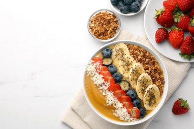 Photo of Delicious smoothie bowl with fresh berries, banana, coconut flakes and granola on white table, flat lay. Space for text