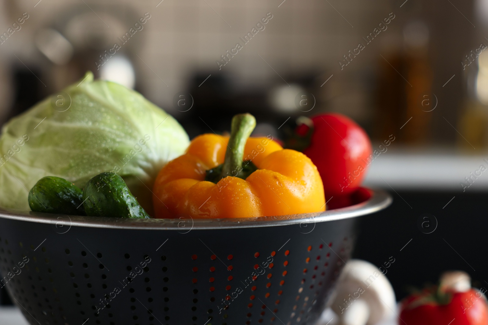 Photo of Metal colander with different wet vegetables on table, closeup