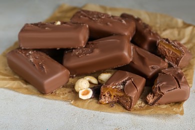 Photo of Delicious chocolate candy bars with nuts on light table, closeup