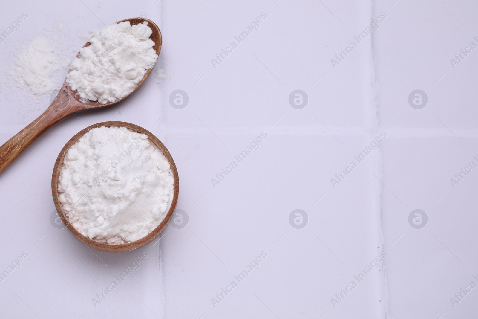 Photo of Wooden bowl and spoon of natural starch on white tiled table, flat lay. Space for text