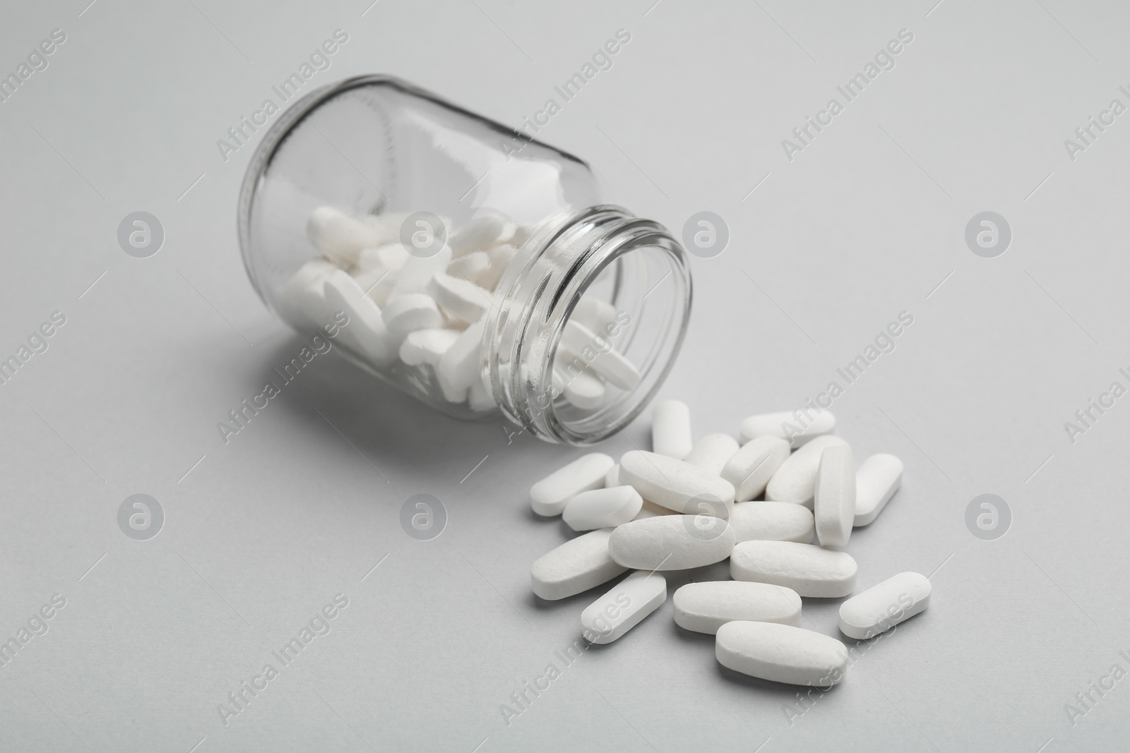 Photo of Vitamin pills and bottle on grey background, closeup