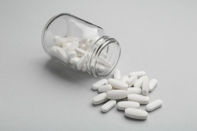 Vitamin pills and bottle on grey background, closeup