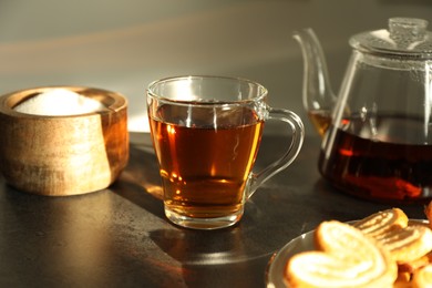 Photo of Tasty tea and sugar on dark table, closeup