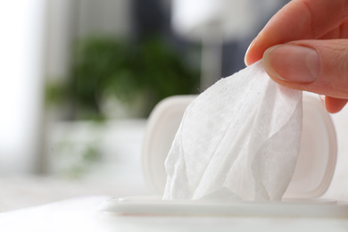 Photo of Woman taking wet wipe from pack on blurred background, closeup