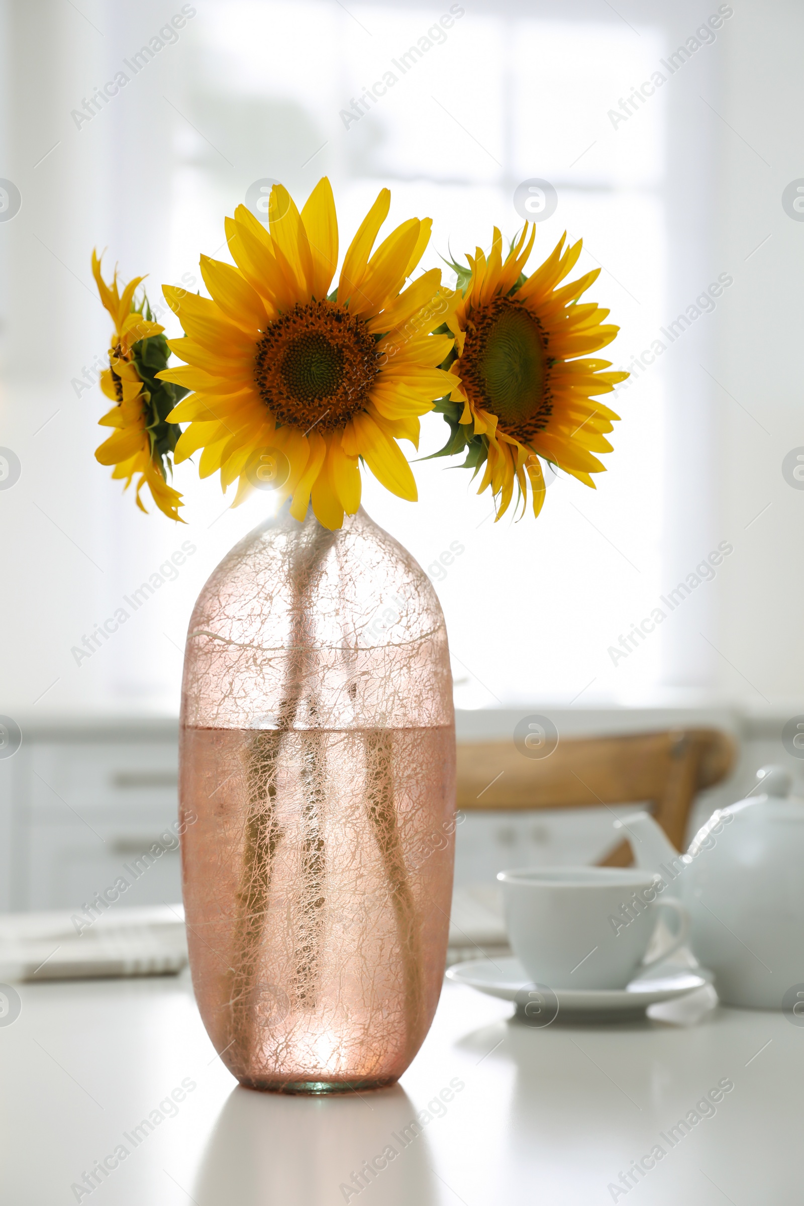 Photo of Bouquet of beautiful sunflowers on table in kitchen