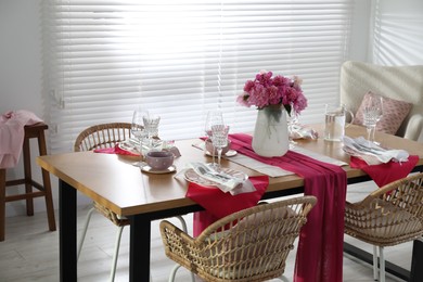 Photo of Pink peonies on table with beautiful setting and rattan chairs in dining room