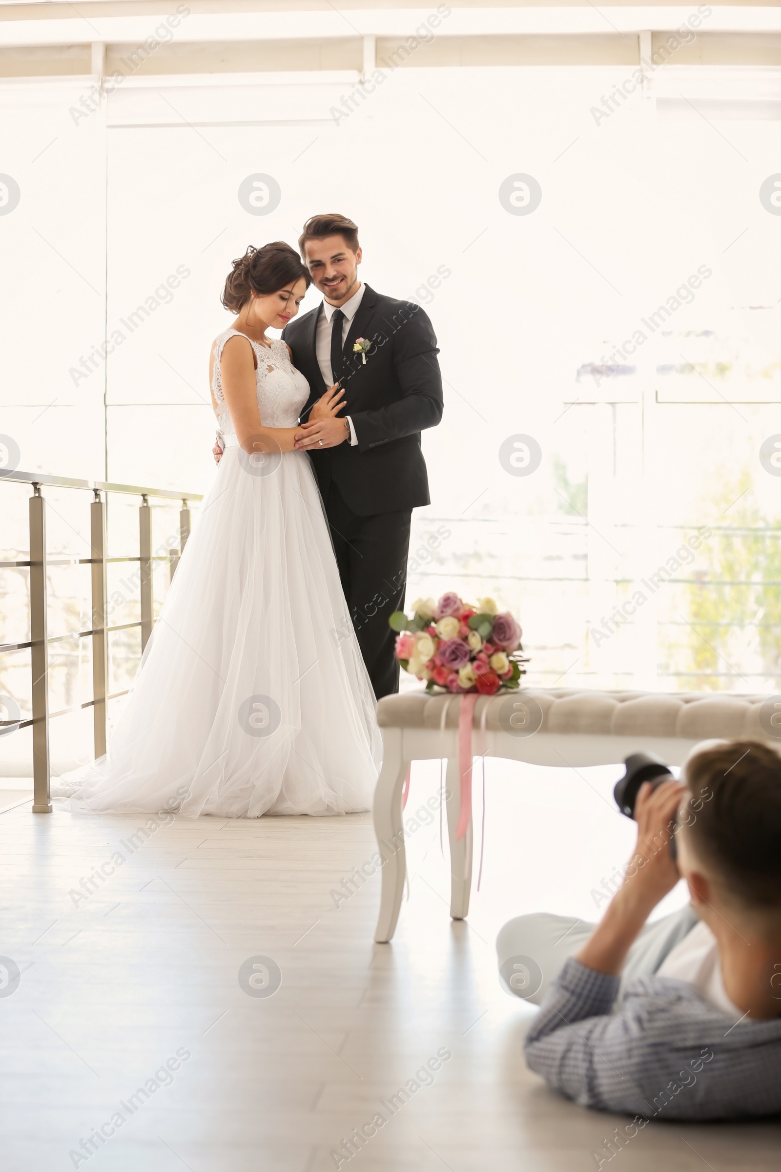 Photo of Professional photographer taking photo of wedding couple in studio