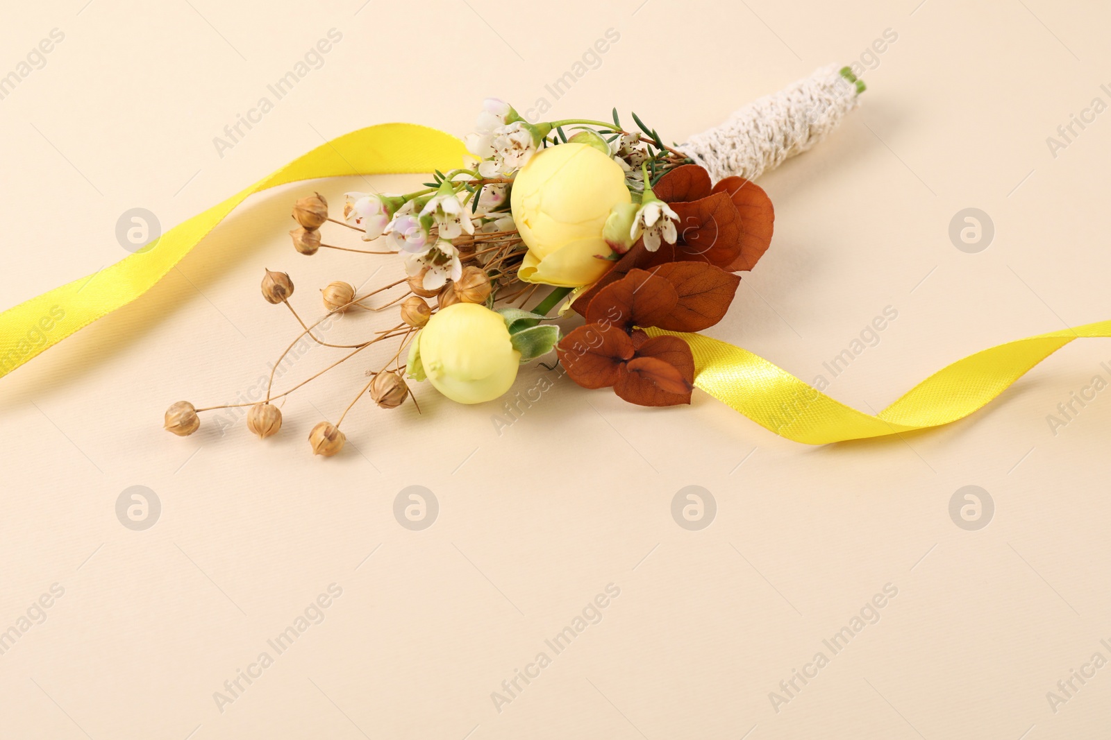 Photo of Stylish boutonniere and ribbon on beige background