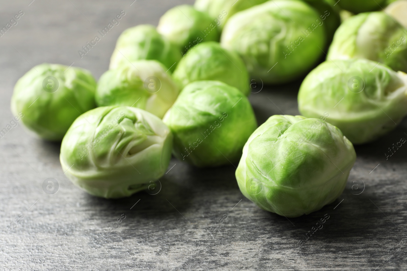 Photo of Fresh Brussels sprouts on grey table, closeup