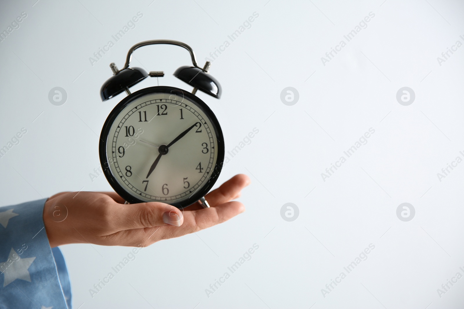 Photo of Woman holding alarm clock on white background, closeup. Morning time