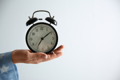 Photo of Woman holding alarm clock on white background, closeup. Morning time
