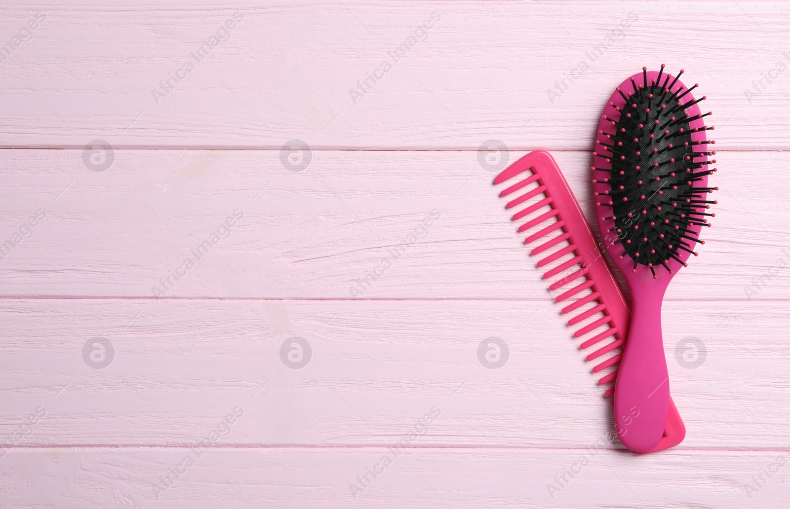 Photo of Hair brush and comb on pink wooden background, flat lay. Space for text
