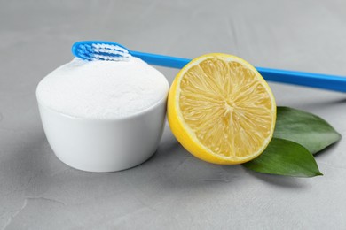 Photo of Toothbrush, lemon and bowl of baking soda on grey table