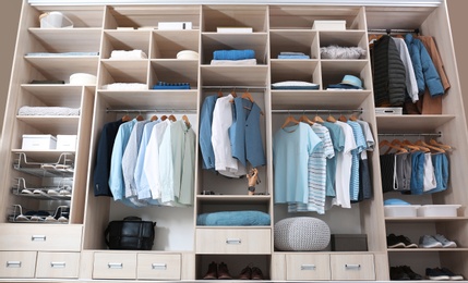 Photo of Stylish clothes, shoes and home stuff in large wardrobe closet