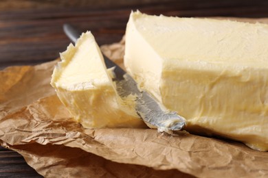 Photo of Tasty homemade butter and knife on parchment, closeup