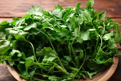 Photo of Fresh coriander in bowl on table, closeup