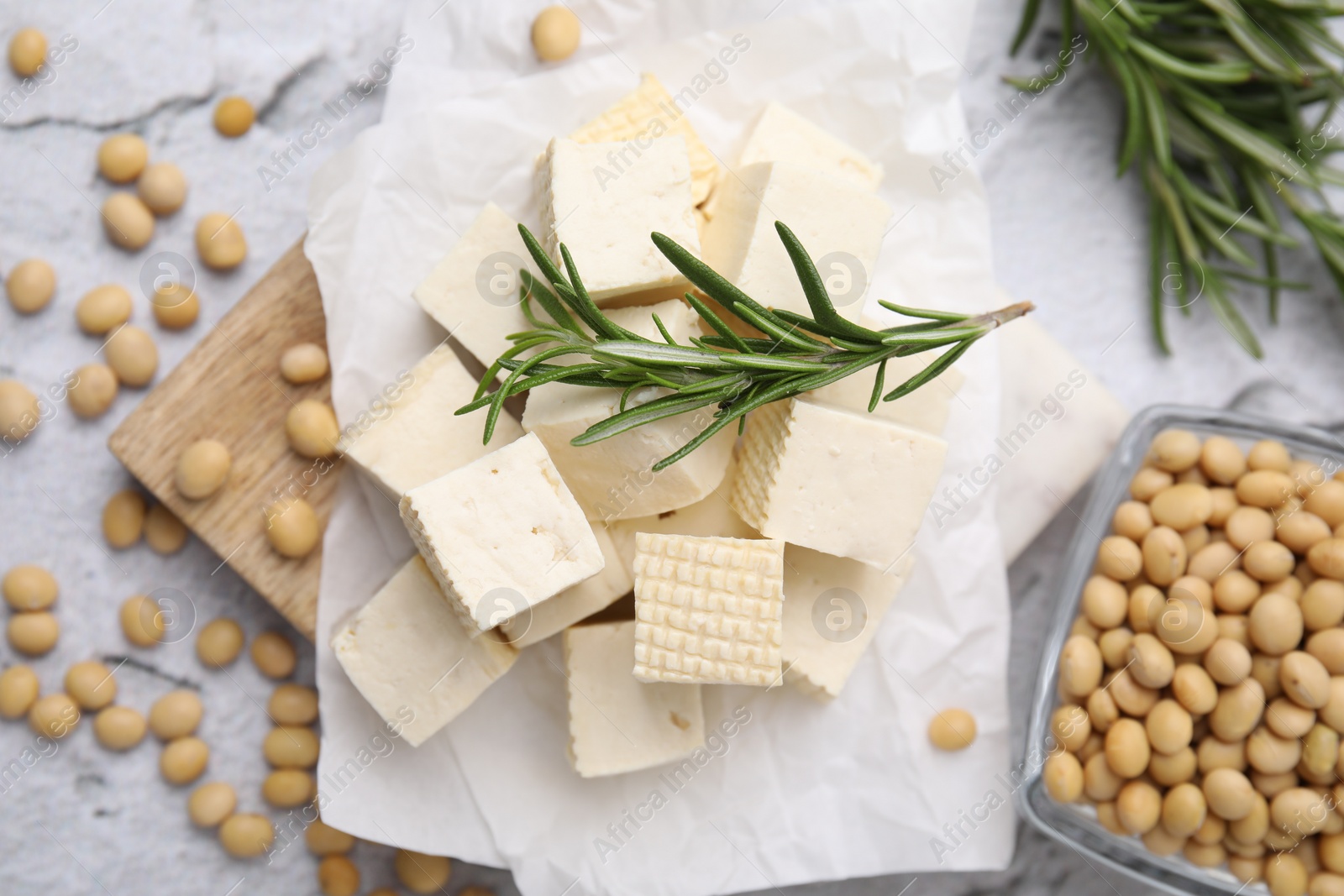 Photo of Delicious tofu cheese, rosemary and soybeans on light gray textured table, flat lay