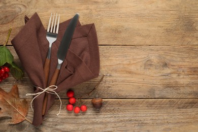 Photo of Autumn table setting. Cutlery, napkin and berries on wooden background, flat lay with space for text