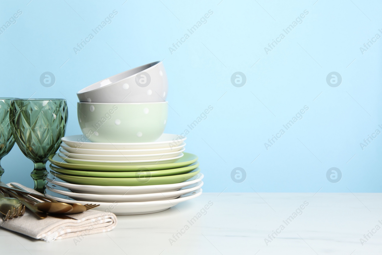 Photo of Beautiful ceramic dishware, glasses and cutlery on white marble table. Space for text