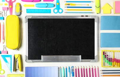Photo of Flat lay composition with different school stationery and small chalkboard on wooden background