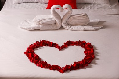 Photo of Honeymoon. Swans made with towels and beautiful rose petals on bed
