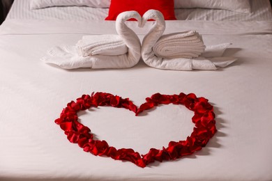 Honeymoon. Swans made with towels and beautiful rose petals on bed