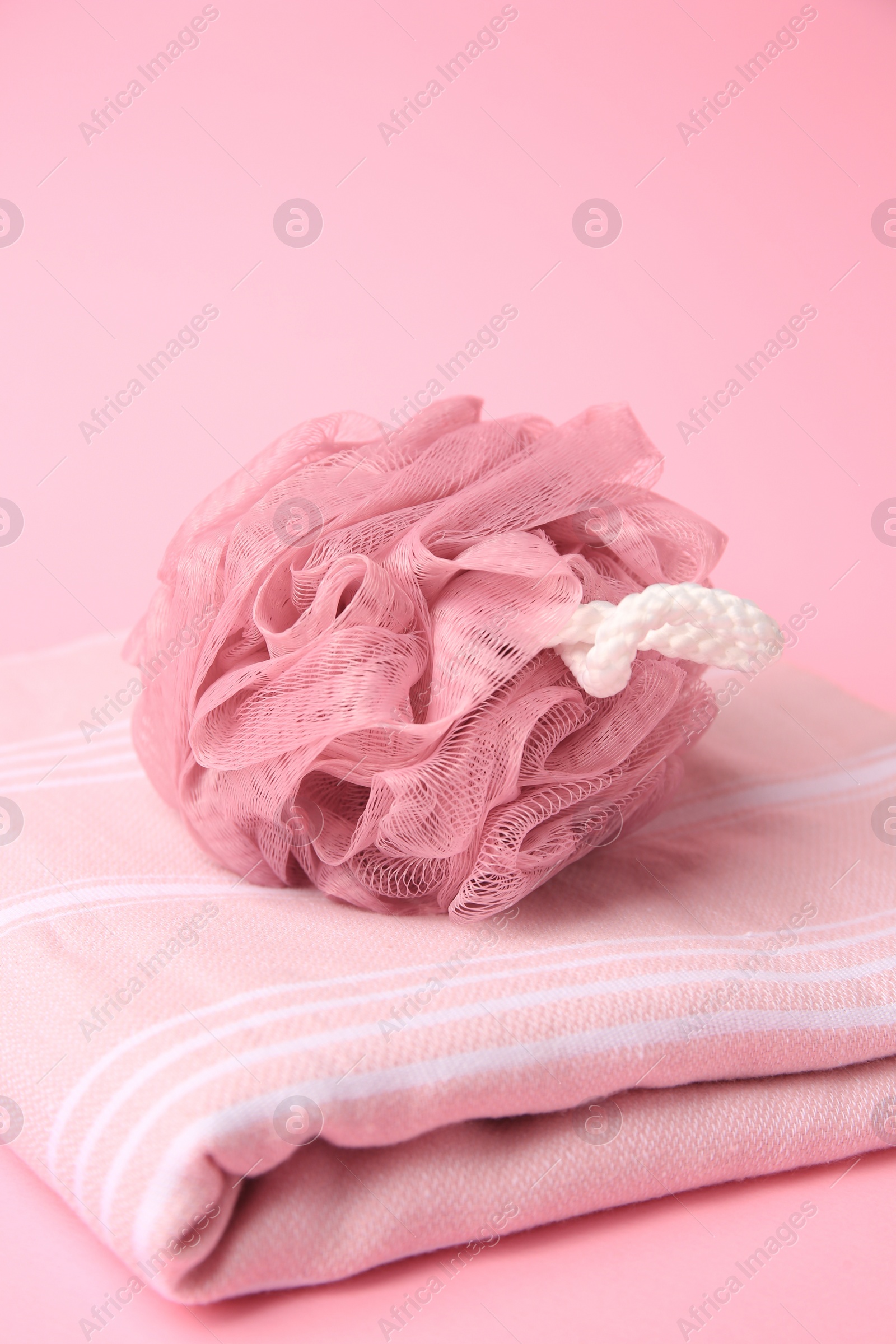 Photo of Shower puff with towel on pink background, closeup