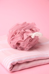 Shower puff with towel on pink background, closeup