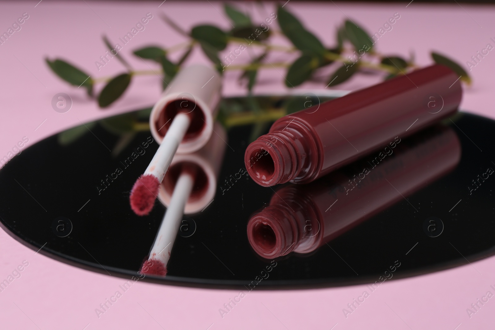 Photo of Lip gloss and mirror on pink background, closeup