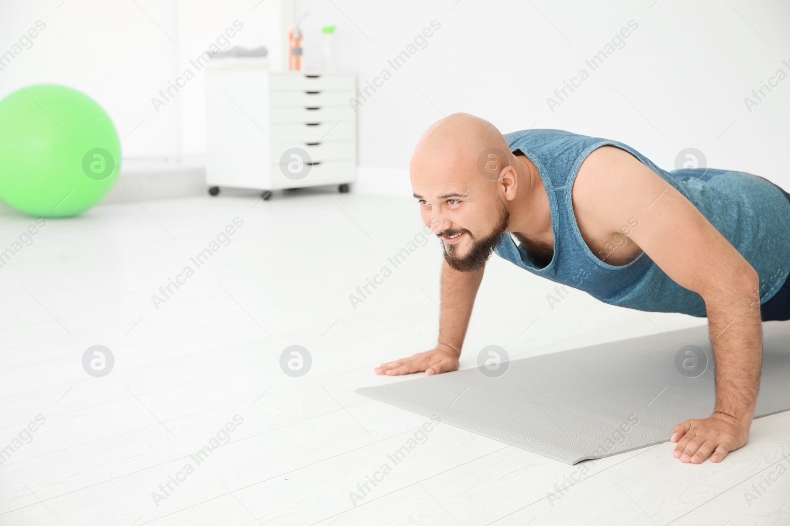 Photo of Overweight man doing exercise on floor in gym