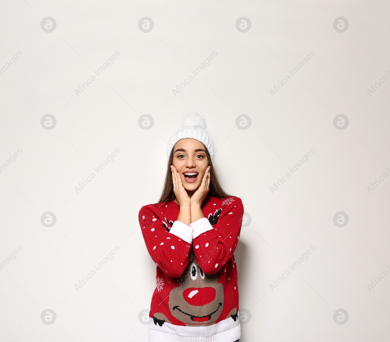 Photo of Young woman in Christmas sweater and knitted hat on white background